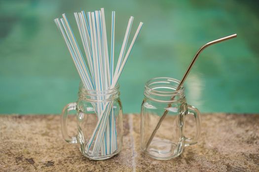 Steel drinking vs disposable straws on pool background. Zero waste concept.
