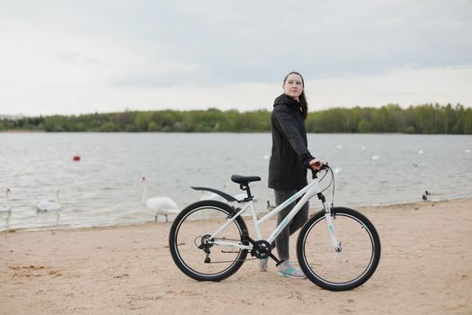 A young woman with a bicycle on the lake.