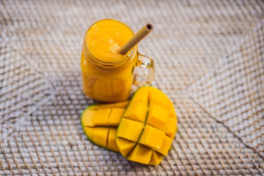 Glass of mango smoothie with bamboo drinking straw. Exotic vacation, chill out drink concept.