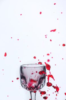 A splash of red wine in a glass on a white background. Cutout.