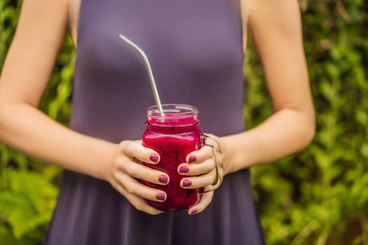 Dragon fruit smoothie with steel drinking straw in female hands.