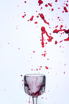 A splash of red wine in a glass on a white background. Cutout.