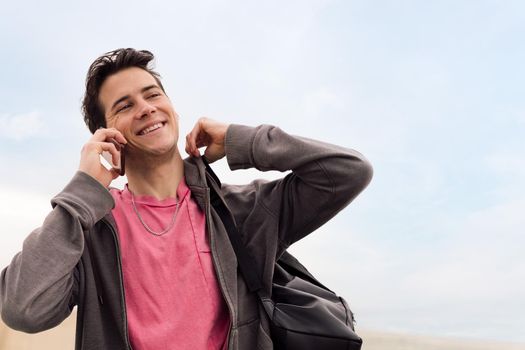 smiling happy young man talking on mobile phone, concept of communication and urban lifestyle, copy space for text
