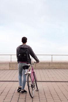 rear view of a young man walking with a bicycle, concept of sustainable transportation and urban lifestyle, copy space for text