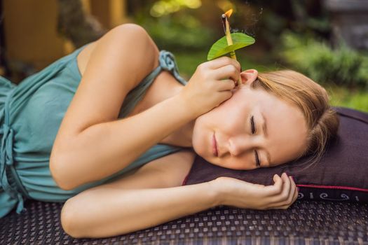 Ear candling being carried out on an attractive caucasian woman in a spa.
