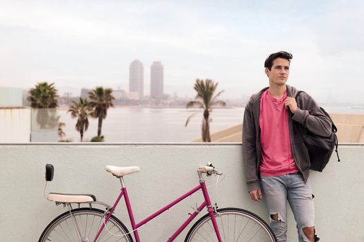 stylish young urban man in front of the city with his vintage bicycle, concept of youth and active lifestyle, copy space for text