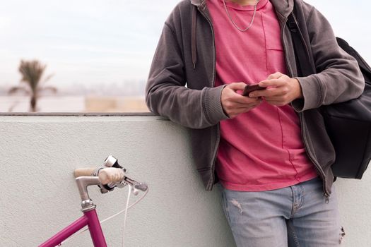 unrecognizable young man with his bicycle using phone, concept of technology and urban lifestyle, copy space for text