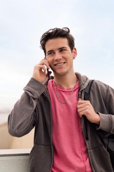 vertical photo of a smiling happy young man talking on mobile phone, concept of communication and urban lifestyle