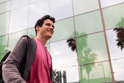 happy young man smiling and walking through the city, concept of youth and urban lifestyle, copy space for text