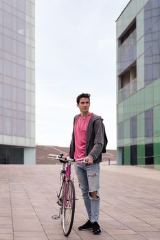 vertical photo of a young man standing holding a retro bike, concept of sustainable urban transportation and ecological lifestyle, copy space for text