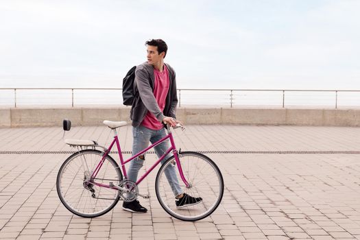 stylish young man walking with a vintage bike, concept of sustainable transportation and urban lifestyle, copy space for text