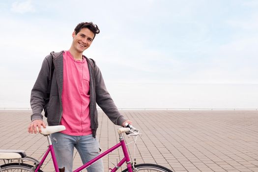 happy young man smiling and holding a retro bicycle, concept of ecological and sustainable urban transportation, copy space for text
