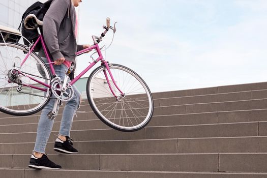 unrecognizable young man carrying bicycle up the stairs, concept of sustainable urban transportation and ecological lifestyle, copy space for text