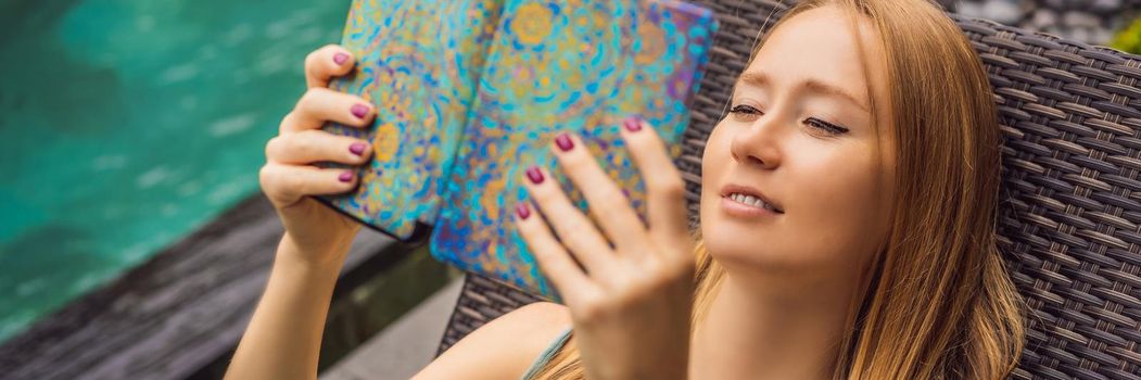 Woman reads e-book on deck chair in the garden. BANNER, LONG FORMAT