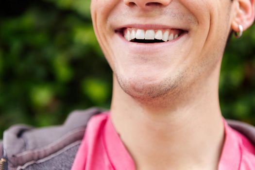 detail of the mouth of a happy young man smiling showing the teeth, concept of happiness and dental health