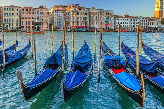 Gondolas moored in water of Grand Canal waterway in Venice. Baroque style colorful buildings along Canal Grande and bell tower Campanile di San Marco. Typical Venice cityscape, Veneto Region, Italy