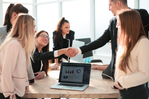 happy employees shaking hands in the workplace. the concept of successful work