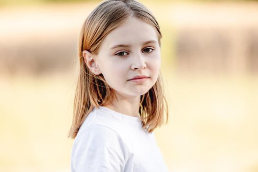 Little girl smiling in sunny spring day outdoors portrait. Cute child kid at nature