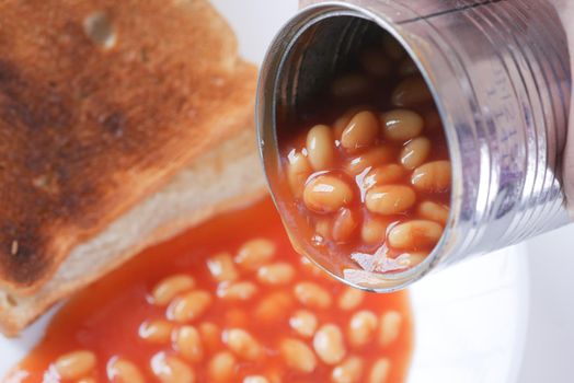 Tasty baked beans pouring from a can container, selective focus