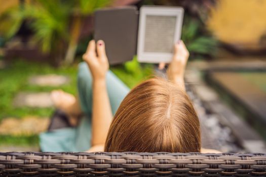 Woman reads e-book on deck chair in the garden.