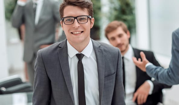 young businessman in glasses on an office background . business concept
