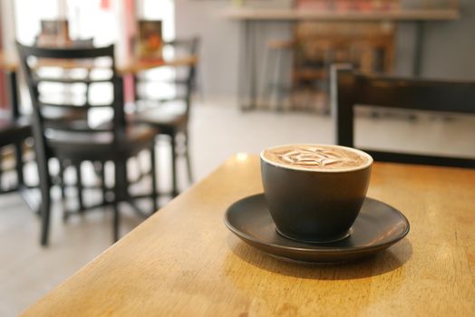a cup of late coffee with flower shape design on top at cafe .