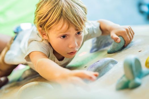 little boy climbing a rock wall in special boots. indoor.