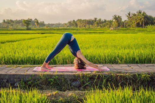 Young woman practice yoga outdoor in rice fields in the morning during wellness retreat in Bali.
