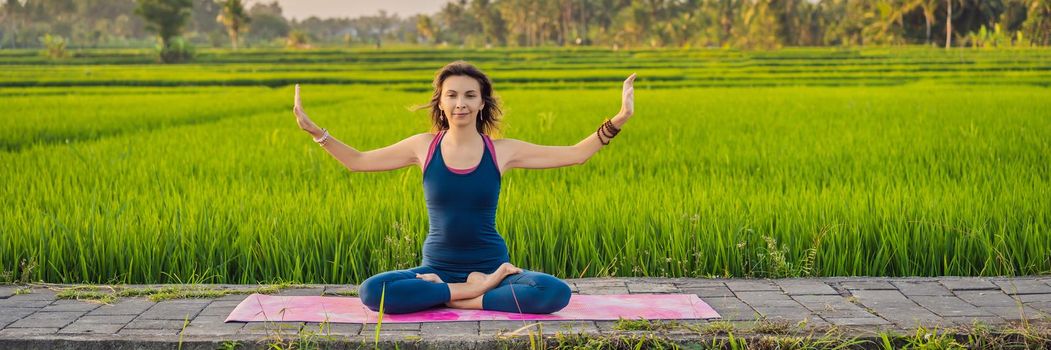 Young woman practice yoga outdoor in rice fields in the morning during wellness retreat in Bali. BANNER, LONG FORMAT