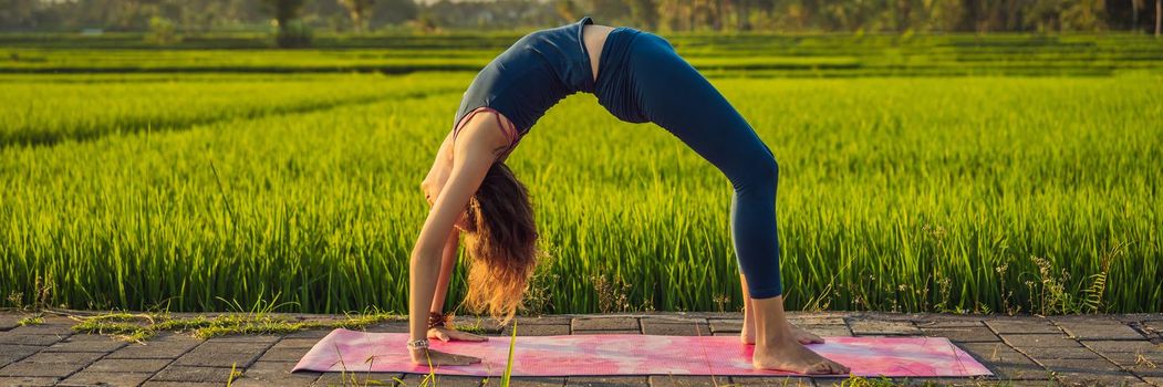 Young woman practice yoga outdoor in rice fields in the morning during wellness retreat in Bali. BANNER, LONG FORMAT
