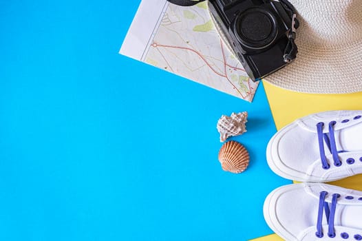 Travel kit with hat, travel card, white sneakers and camera on a blue background.Travel flat lay.