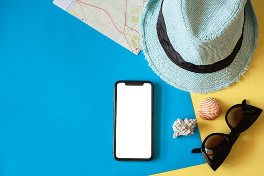 Travel kit with hat, travel card, smartphone and sunglasses on a blue background.Travel flat lay.