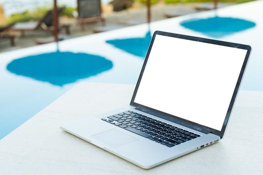 A laptop with an empty screen stands in the courtyard of a beautiful home garden, in Sunny weather