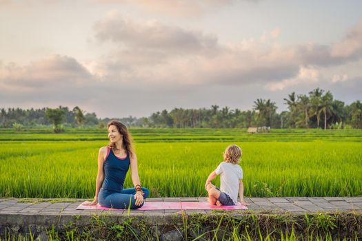 Boy and his yoga teacher doing yoga in a rice field.