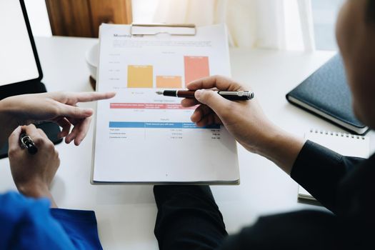 Teamwork concept, consultation, male economist holding pen pointing to budget, finance and investment documents, discussing and planning finances with female advisors in conference room