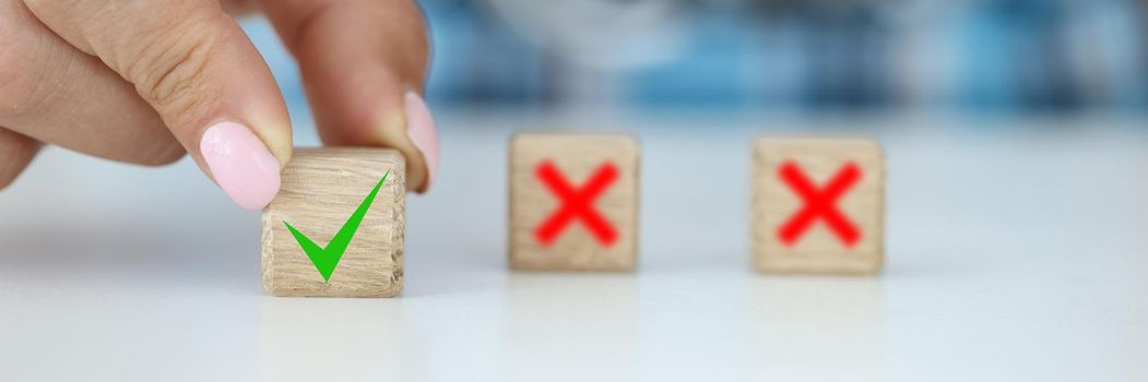 Female fingers line up wooden cubes on the table, close-up. Dilemma and choice concept, decision making, failure and luck