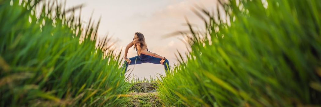 Young woman practice yoga outdoor in rice fields in the morning during wellness retreat in Bali. BANNER, LONG FORMAT