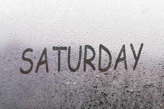 saturday written on the glass screen with raindrops background