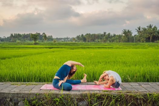 Boy and his yoga teacher doing yoga in a rice field.