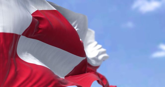 The flag of Greenland waving in the wind on a clear day. Greenland is the world's largest island, and one of the three constituent countries that form the Kingdom of Denmark,