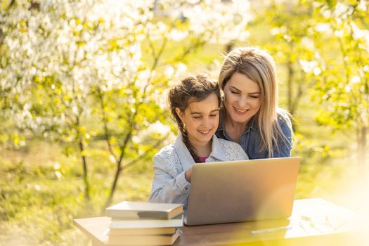 childhood, parenting and technology concept - happy mother with adorable little girl with laptop