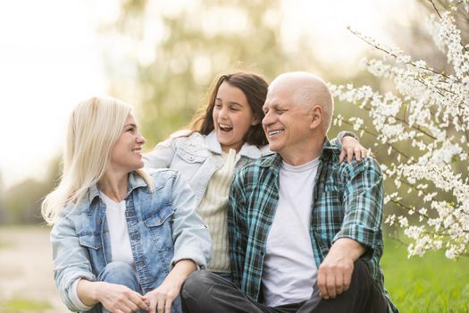 grandfather with granddaughter and daughter in spring, senior man in the yard.