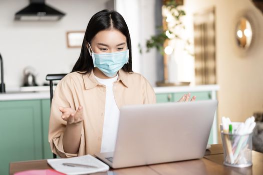 Young asian woman, student talking on video conference, attend lecture in medical face mask, online studying while on quarantine.
