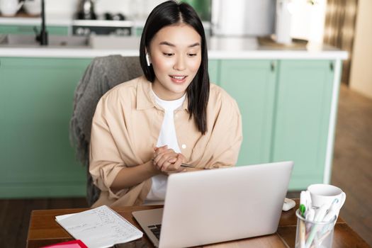 Young corporate woman working from home. Asian girl has online classes remotely, talking on video chat, internet lecture or webinar.