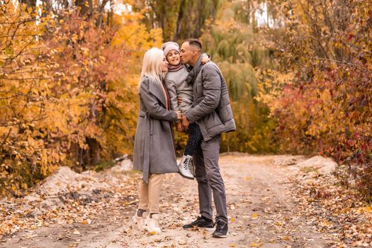 family, childhood, season and people concept - happy family playing with autumn leaves in park.