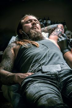 Master showing process of making a tattoo in tatoo salon./Professional tattooist makes tattoo in studio.