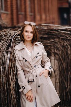 A happy stylish girl in a gray coat walks around the city.