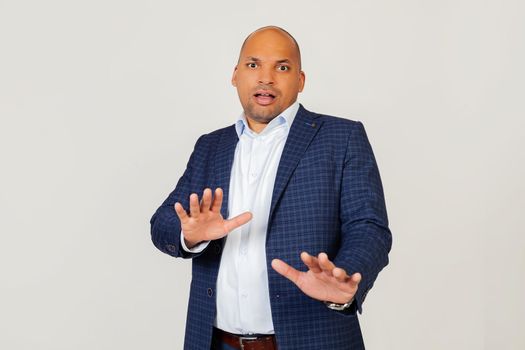 Portrait of shocked young African American businessman guy, scared and frightened by fear expression, stopped hand gesture, shouting in shock. Panic concept. Standing on a gray background