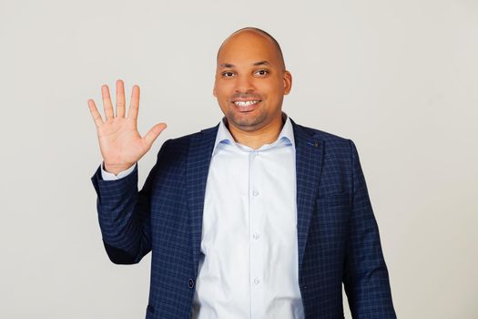 Portrait of successful young African American businessman guy, showing with fingers number five, smiling, confident and happy. The man shows five fingers. Number 5. Standing on a gray background