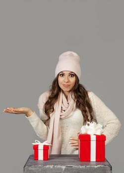 A beautiful young woman in winter clothes, thoughtfully, hesitantly, stands before the choice of a small or large gift for the New Year and Christmas. The girl decides which gift to choose